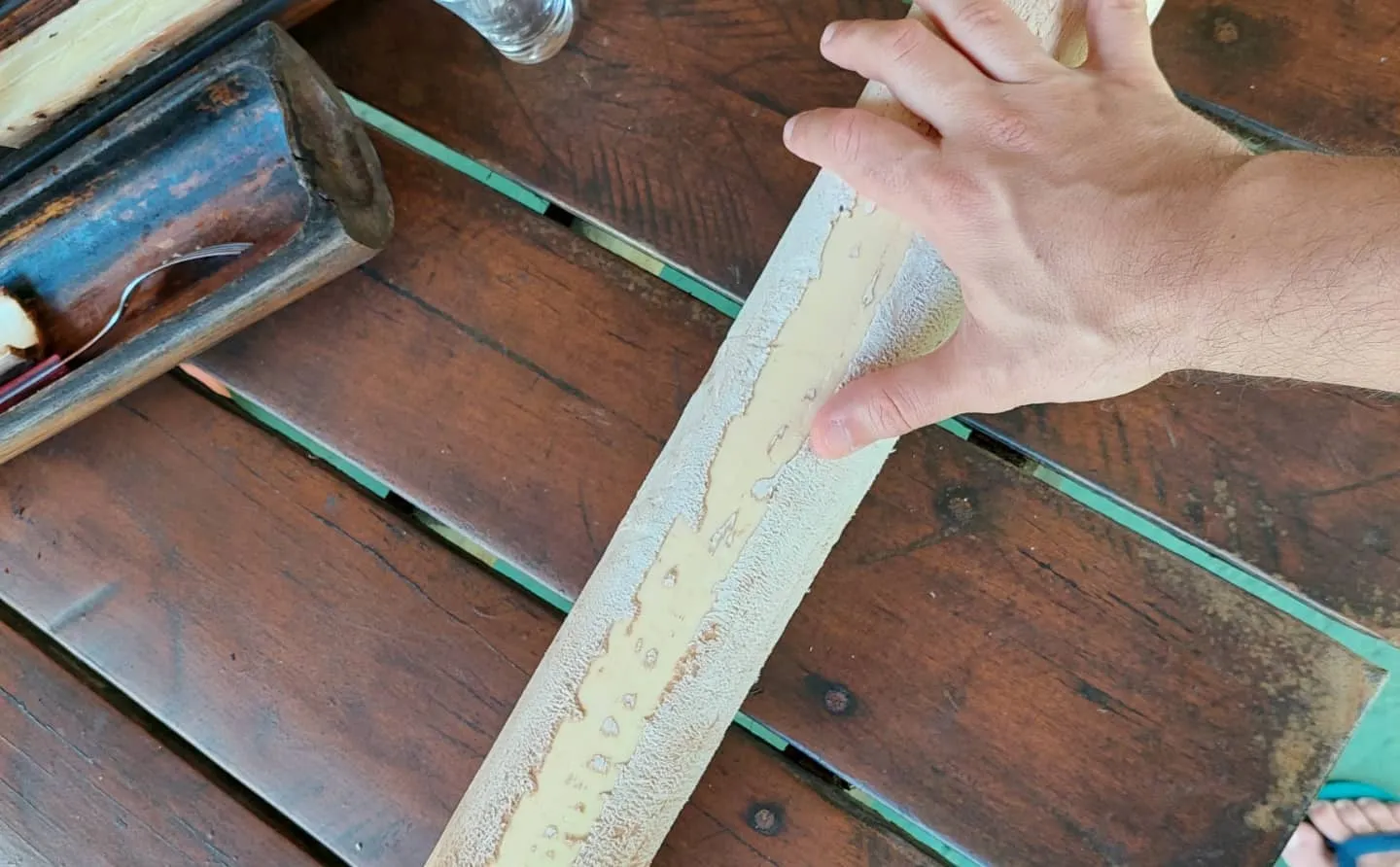 Mão segurando um tronco de palmito descascado sobre uma mesa de madeira