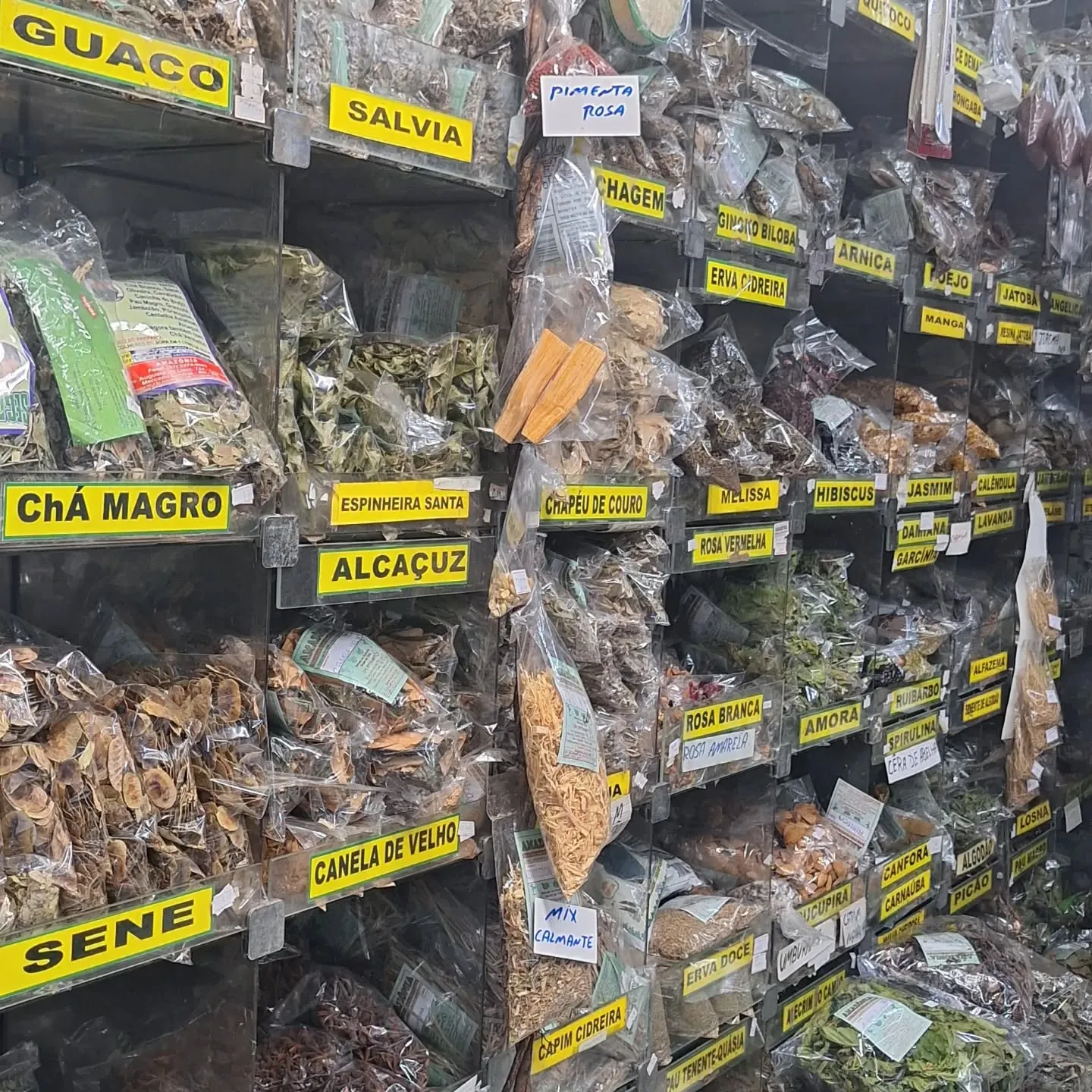 Prateleiras de ervas e chás a granel com etiquetas amarelas